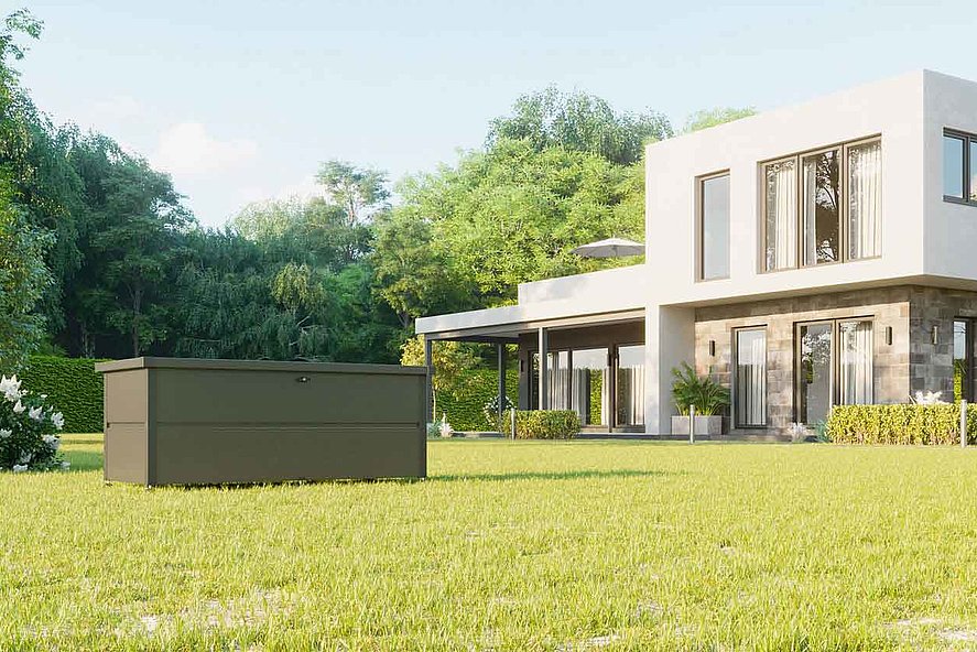 Gartenbox aus Stahl in anthrazit mit eingebautem Schloss steht in einem Garten vor einem modernen Architektenhaus