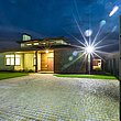 offenes Doppelflügeltor mit Sichtschutz erlaubt Blick in die Einfahrt einer modernen Villa bei Nacht