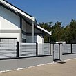 Lamellenzaun zweifärbei, weiße Lamelllen und dunkelgraue Pfosten mit Gartentür vor Einfamilienhaus in Deutschland