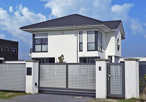 elegantes Schiebetor und Gartentür zweifärbig in grau und dunkelgrau vor alleinstehendem Haus