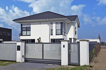 Schiebetor mit Lochblech aus Aluminium in grau vor einem kubisch gebauten Einfamilienhaus