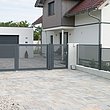 elektrische Doppelflügeltor und Gartenzaun mit Lochblech in grau vor großem Einfamilienhaus mit Garage