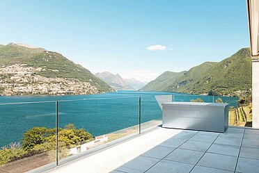 Gartenbox in silber auf moderner Terrasse am Meer mit Geländer aus Glas