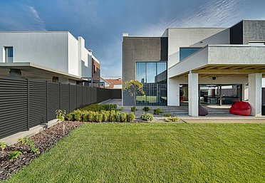 Moderner Sichtschutzzaun aus Aluminium in anthrazit als Grenze zwischen zwei Einfamilienhäusern