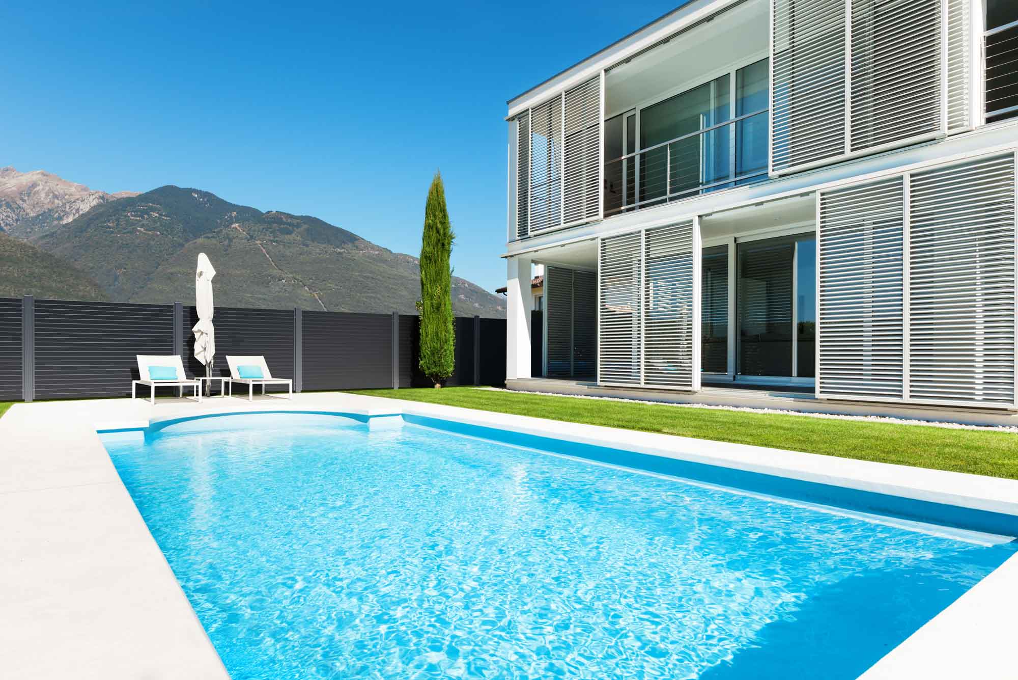 Architektenvilla mit Pool umzäunt von einem modernen Zaun aus Aluminium - Blick auf die Berge
